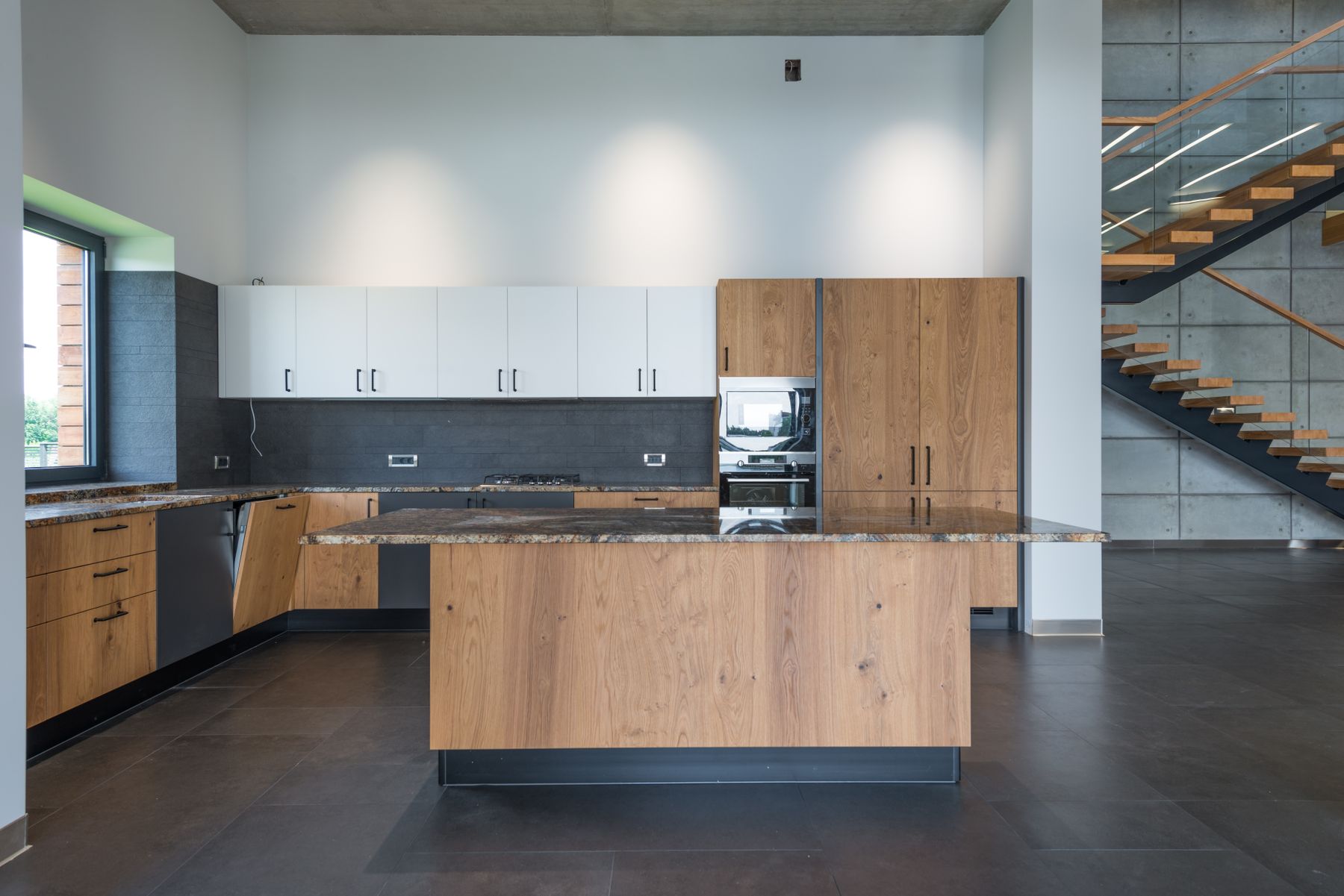 Wood-front island and cabinet run with white upper cabinets and dark surfaces