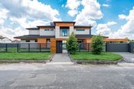 Facade of contemporary luxury villa building with lawn and green trees under blue sky with clouds