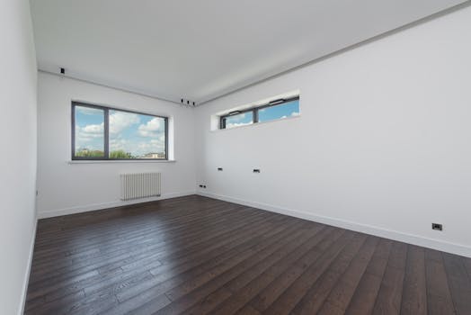 Spacious and clean interior room with hardwood flooring and large windows providing natural light.