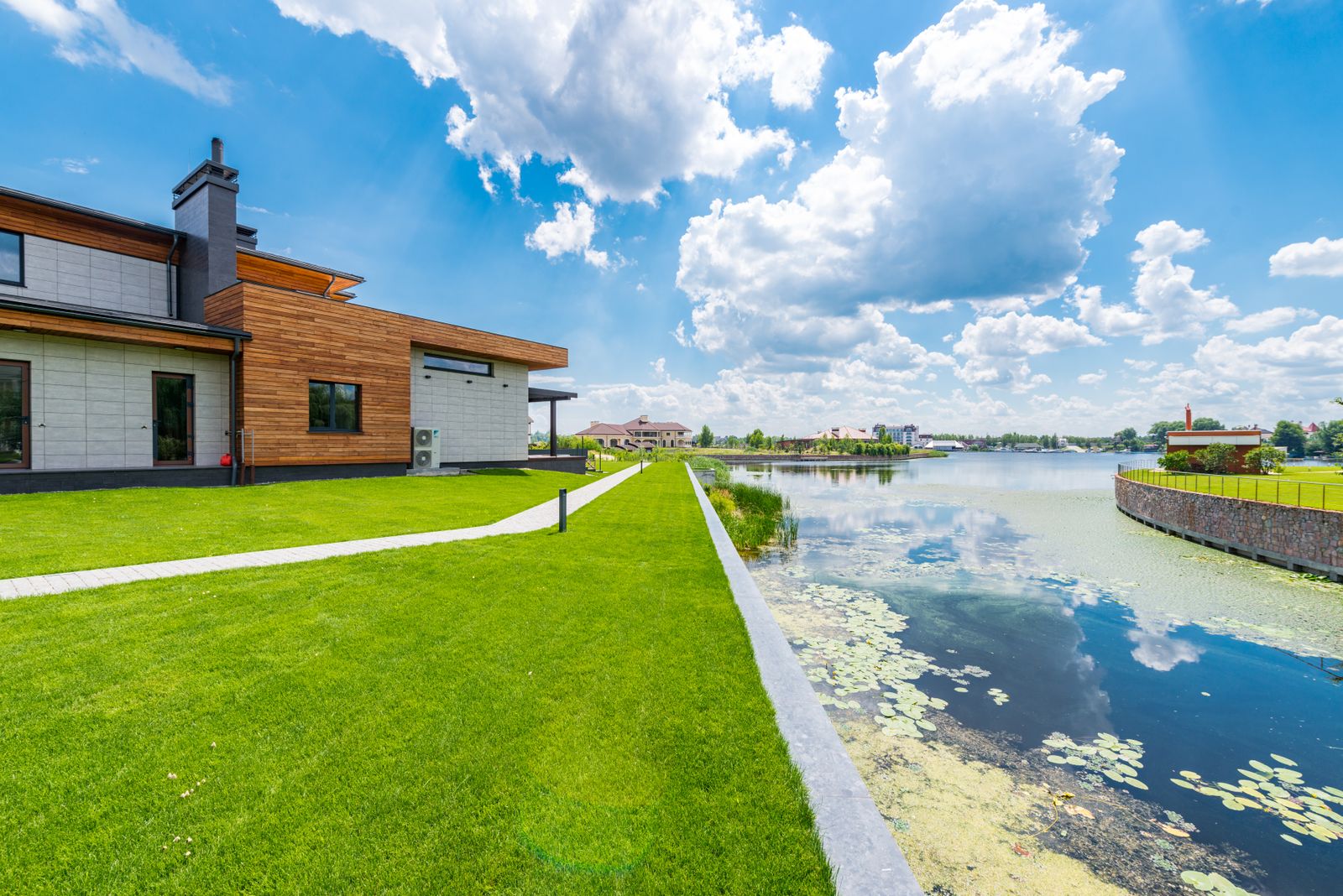 A large modern lakefront villa with a green lawn near the water
