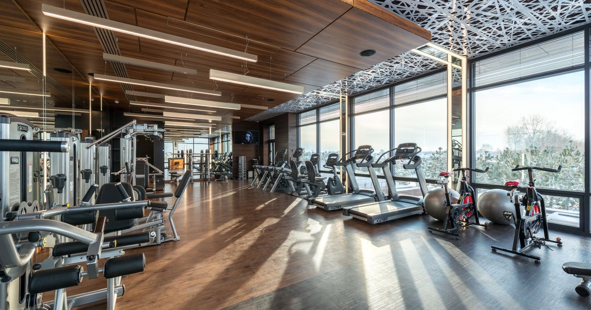 Wnętrze nowoczesnego klubu fitness z rzędami maszyn cardio i sprzętu do treningu siłowego w jasnej, przestronnej sali