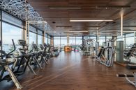 Interior of modern spacious fitness club with various sports machines and equipment placed on parquet floor near panoramic windows