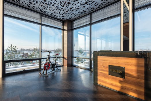 Spacious modern gym featuring an exercise bike with large windows showcasing a scenic outdoor view.
