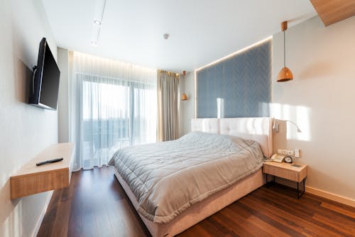 Bedroom interior with bed and nightstands and parquet floor in sunlight