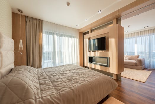 Interior of spacious apartment with cozy living room with soft bed separating from living room with sliding doors and wall with TV set in sunlight