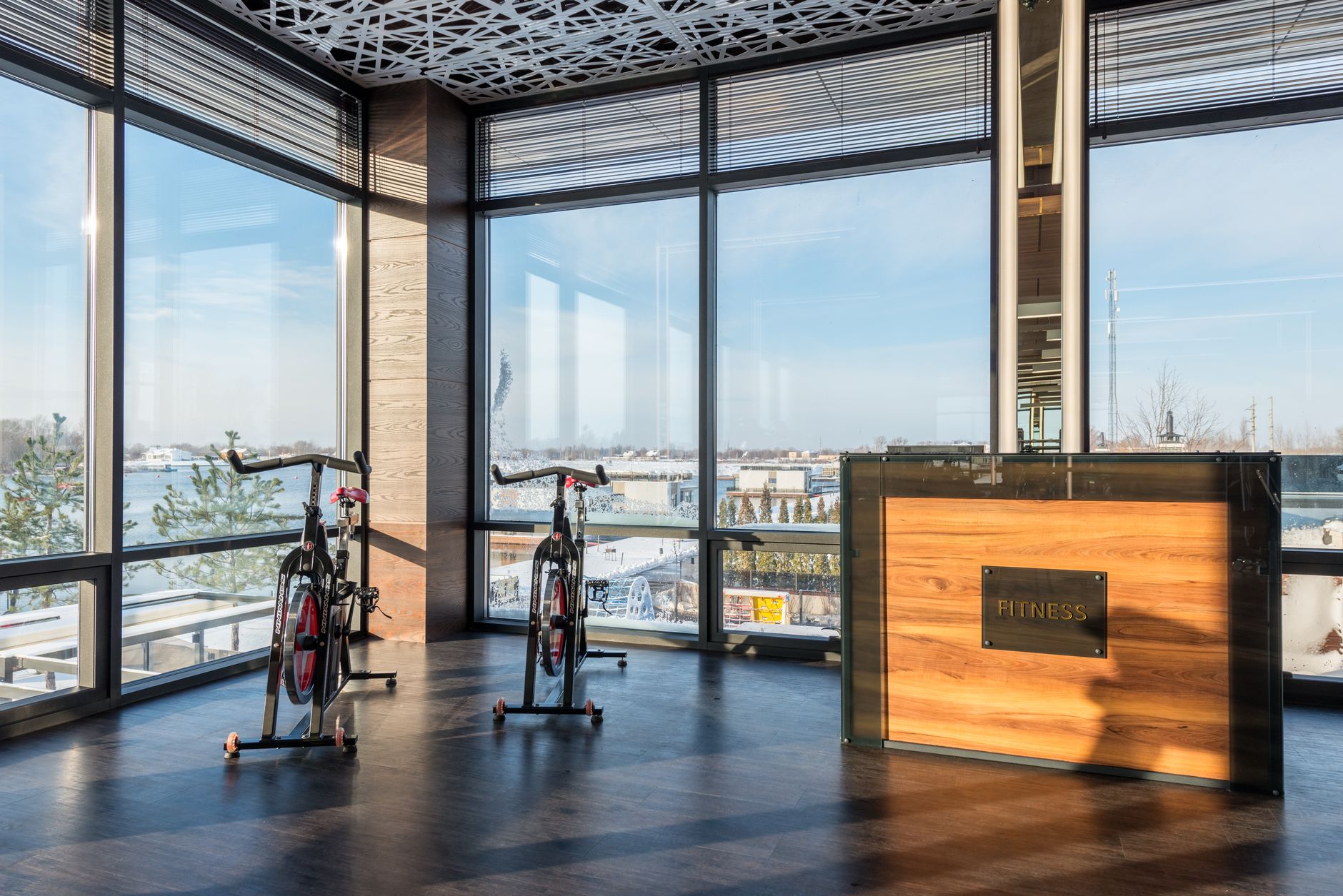 健身訓練週期設計:新手必懂核心概念 Spacious gym interior with stationary bikes overlooking a scenic view through large windows.