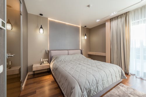 Interior of modern bedroom with cozy bed with quilted coverlet and sliding door in daylight