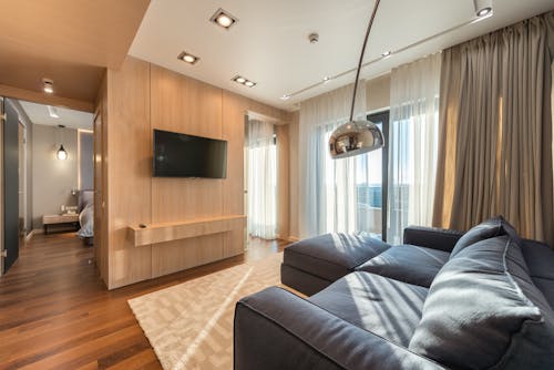 Interior of spacious modern apartment with soft sofa and TV in leaving room and corridor leading to bedroom