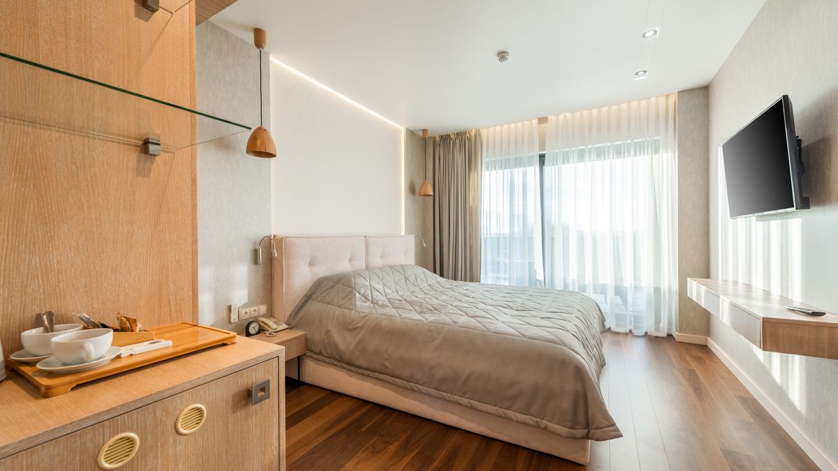 Interior of comfortable bed covered with blanket in bedroom suite in hotel in daylight