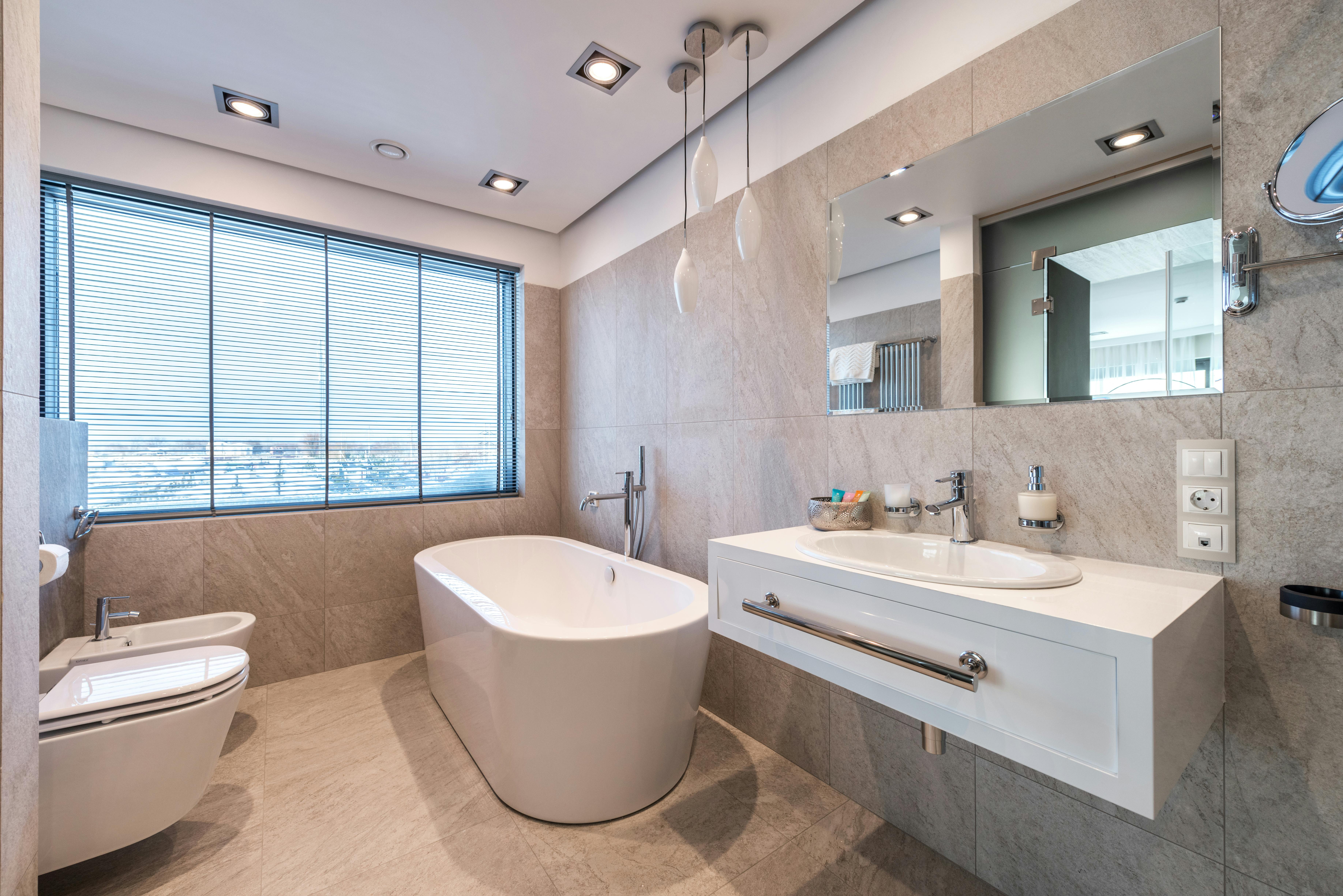 A bright bathroom interior with a freestanding tub near a large window.