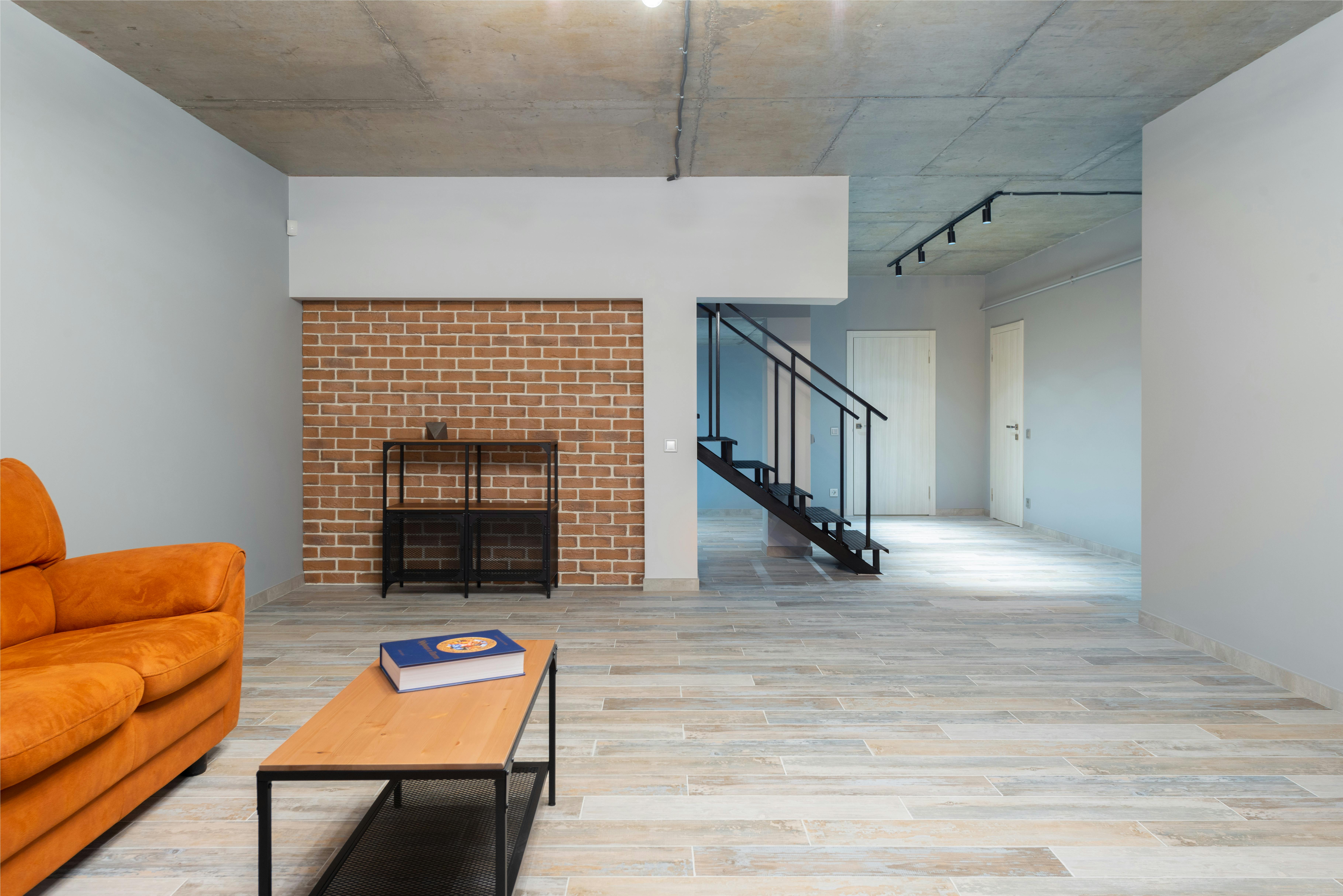Track Lighting In An Industrial Loft Setting With Adjustable Heads Illuminating Art And Shelving, Featuring Black Or Brushed Metal Tracks On High Ceilings