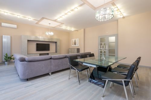 Free Table with candlestick and chairs placed near comfortable couch against modern TV in stylish living room with door and glowing lamps Stock Photo