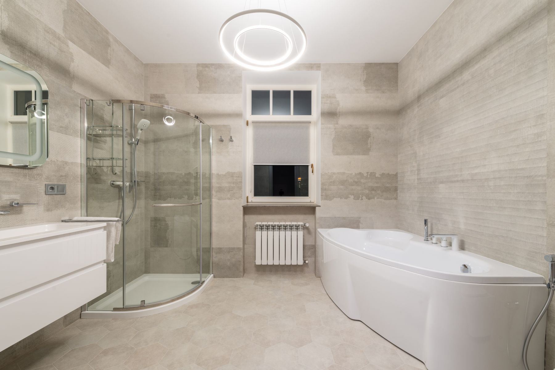 Modern bathroom with bathtub, vanity, window and glass shower enclosure