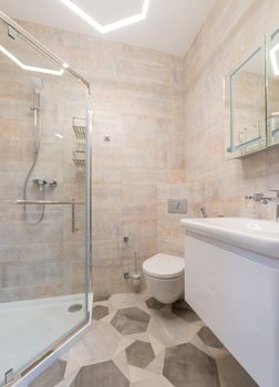 Bright, clean bathroom featuring ceramic tiles, a glass shower, and modern fixtures.