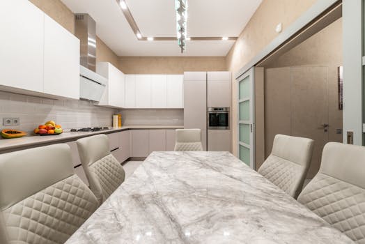 Sleek contemporary kitchen featuring a marble-topped dining table, leather chairs, and modern appliances.