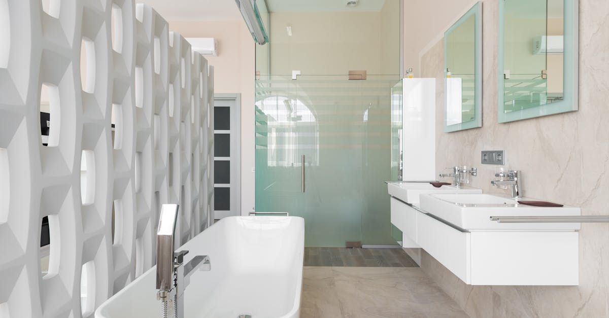 Modern bathroom with white bathtub and glass shower cabin and mirrors over basins