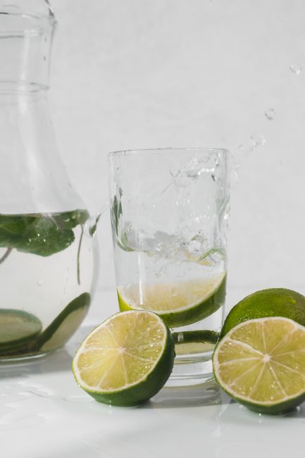 Close-up of lime slices splashing into water, evoking a refreshing summer vibe.