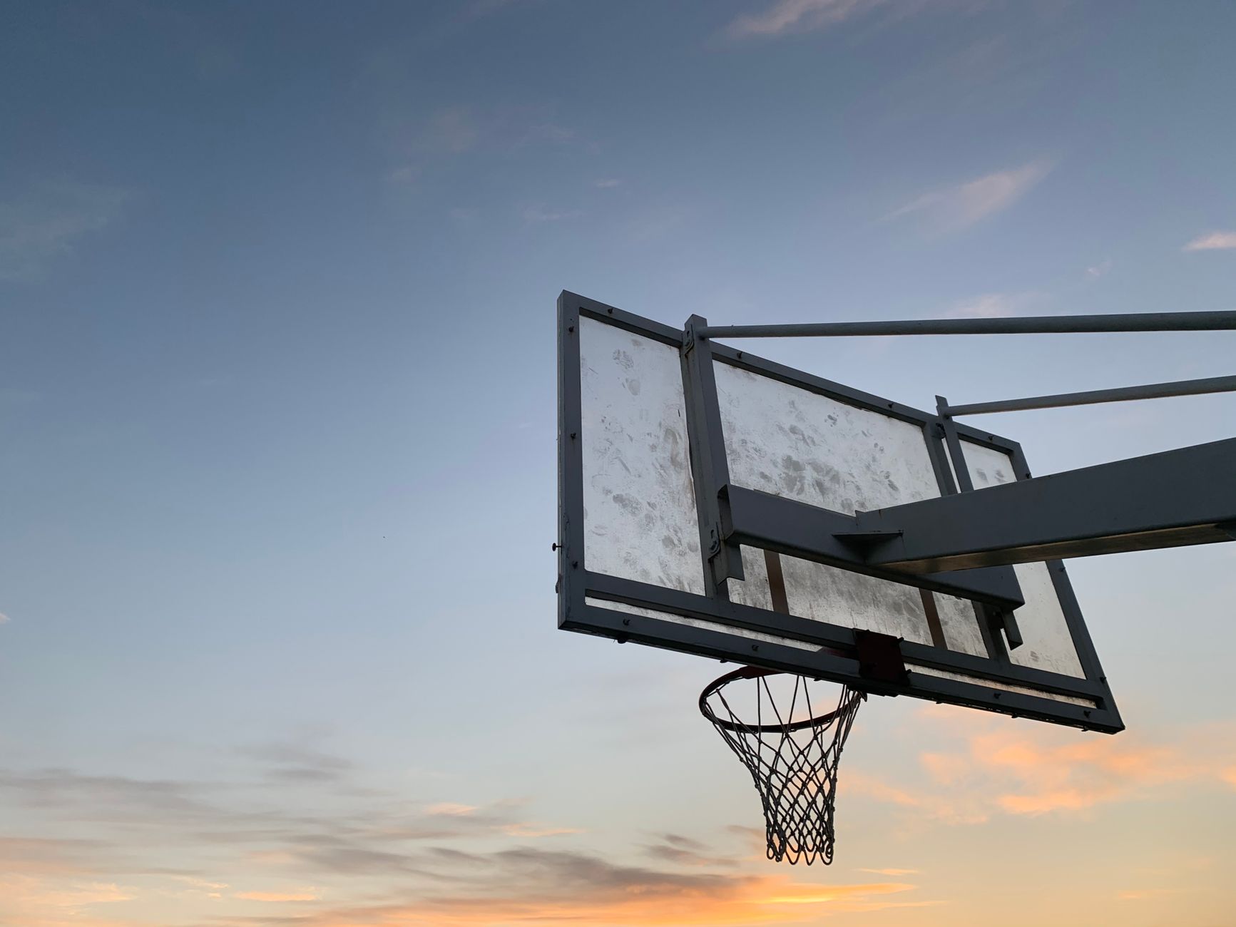 A solitary basketball hoop silhouetted against the evening sky, capturing a peaceful outdoor moment.
