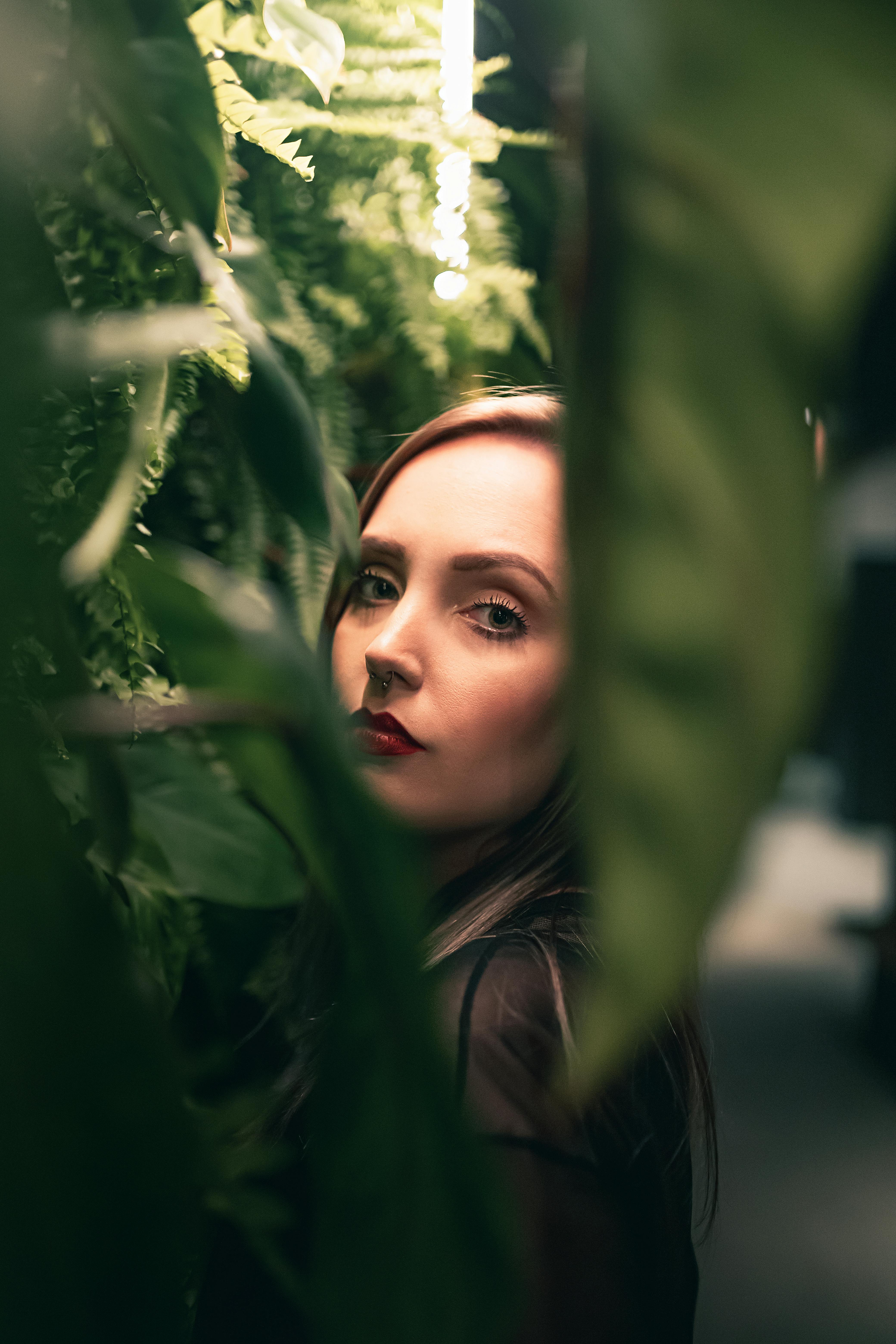 Young content woman among green leaves