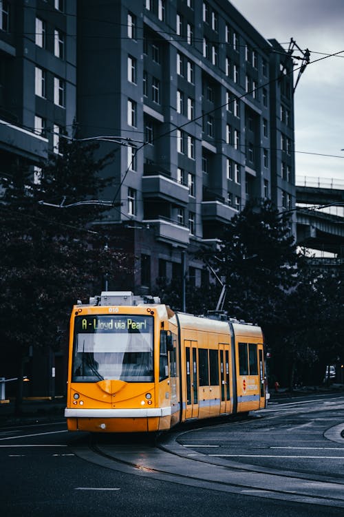 Modern yellow tram riding along street