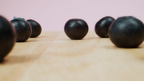 Free Close-up view of scattered blueberries on a wooden surface with a soft pink background. Stock Photo