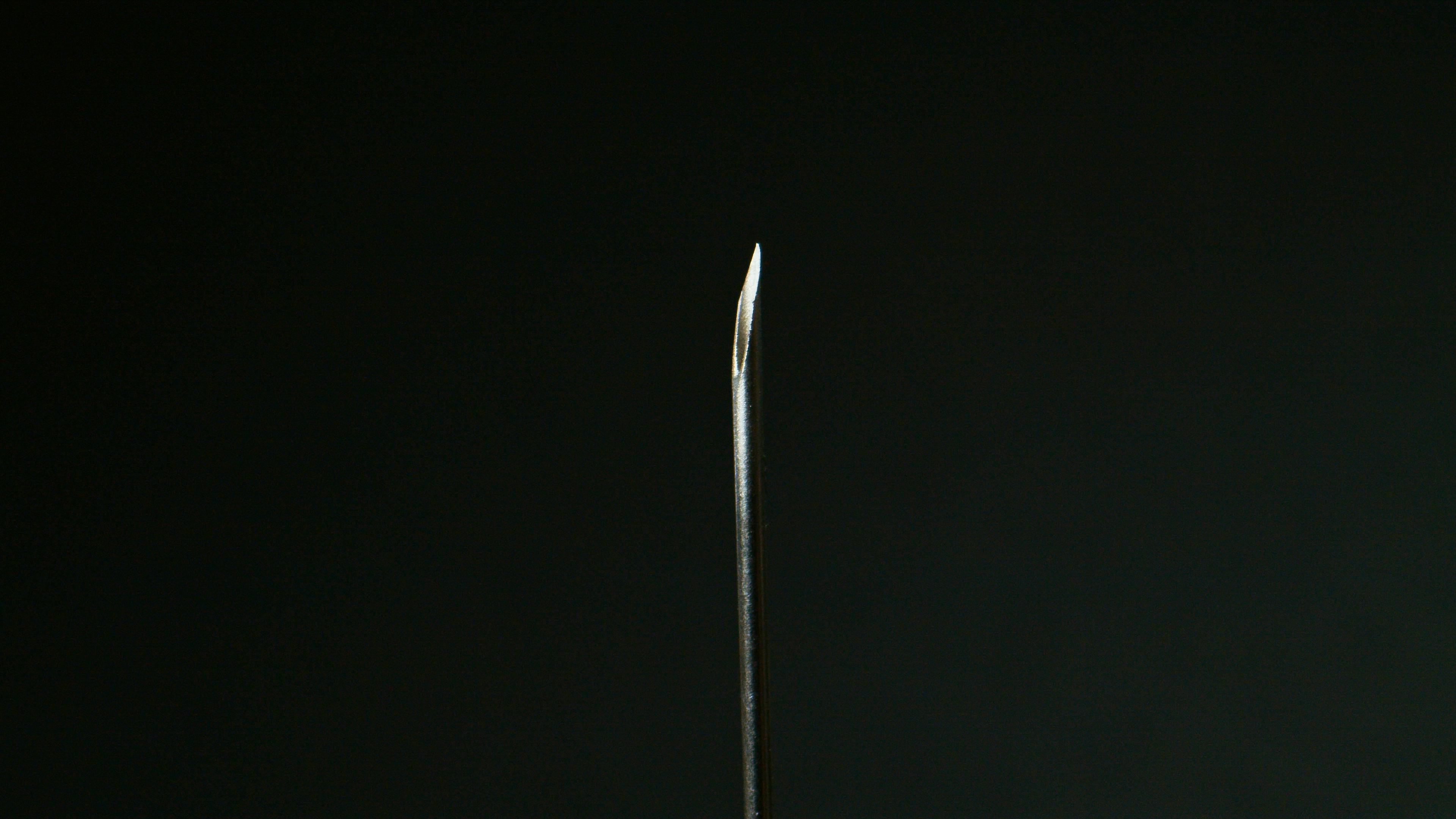 Detailed macro shot of a sharp metal needle against a dark background.