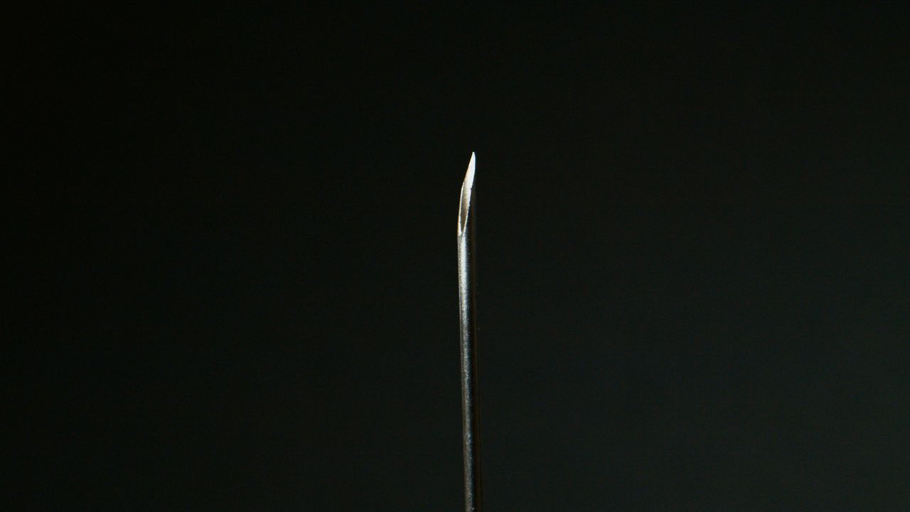detailed macro shot of a sharp metal needle against a dark background