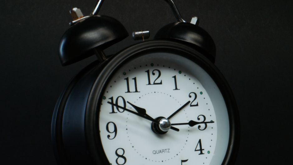 Does a Sunrise Alarm Clock Really Ease Morning Grogginess? Close-up of a vintage black alarm clock against a dark background, showing the time at 10:10.