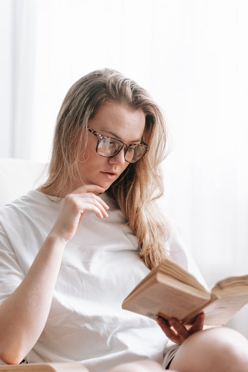 Pensive woman touching chin while reading book