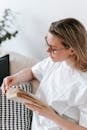 High angle of female sitting on sofa and flipping page of book while spending free time at home