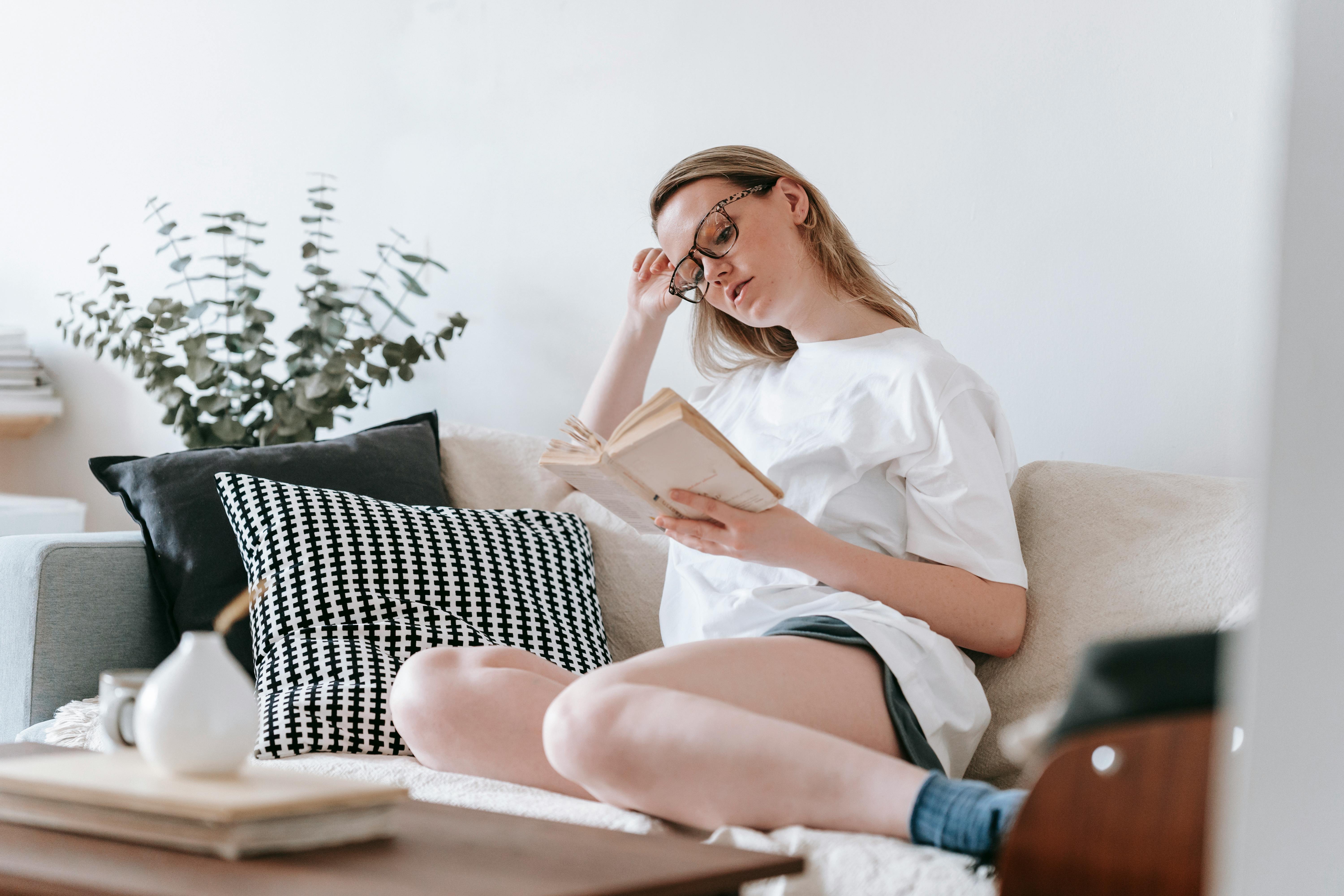 young woman reading on sofa with pillows