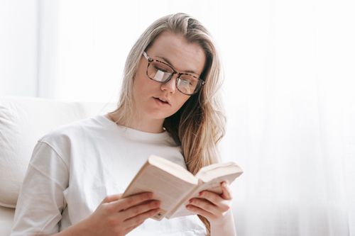 Free Young female with short hair wearing white t shirt reading book while resting at weekend Stock Photo