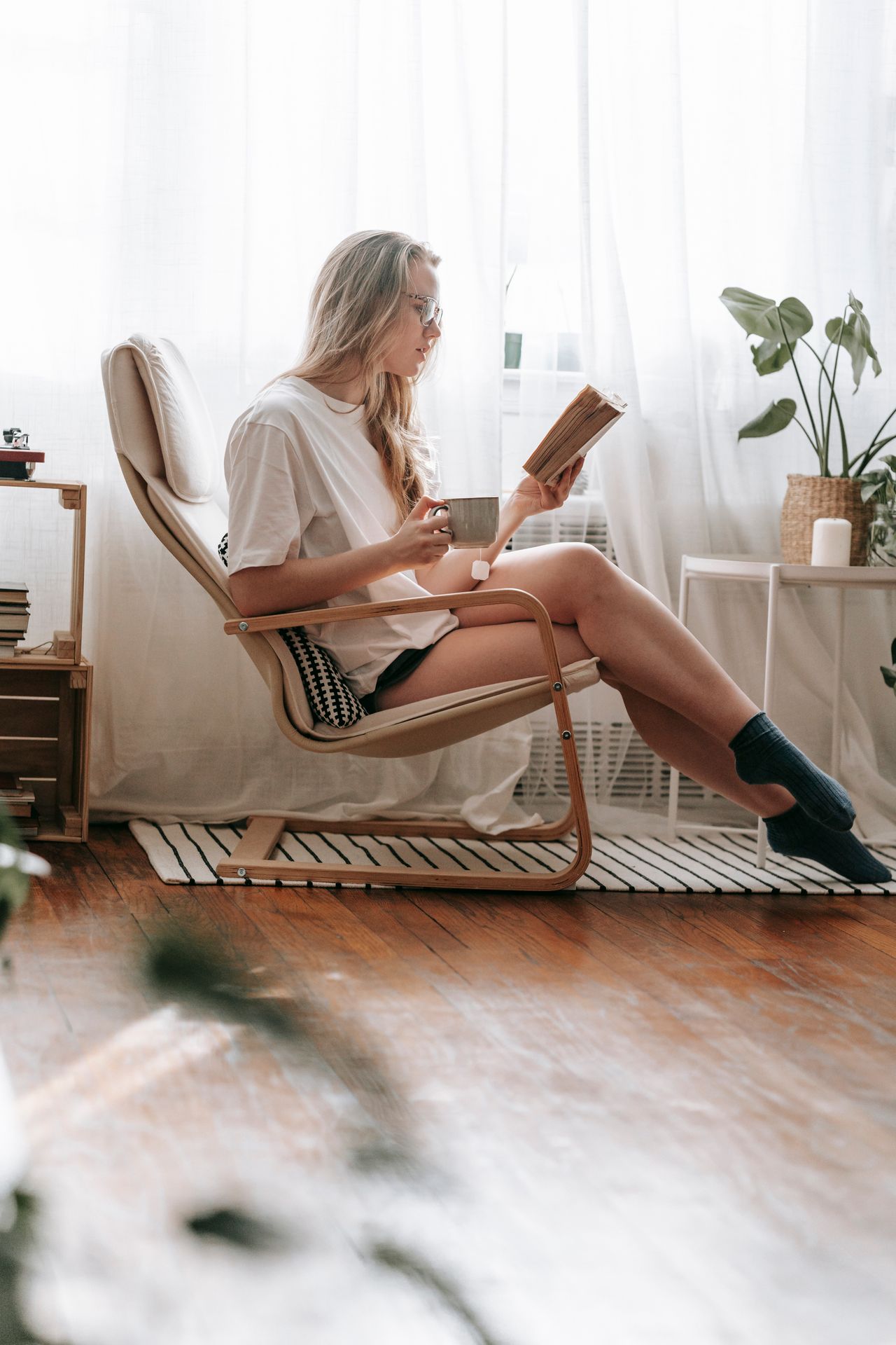 Woman reading a book in a lounge chair by the window