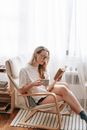 Young woman reading book in armchair