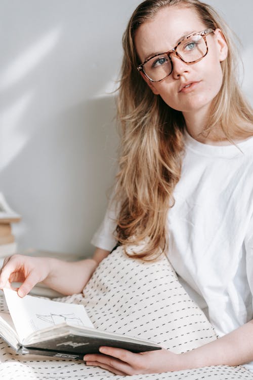 Contemplative woman in eyeglasses with notebook at home