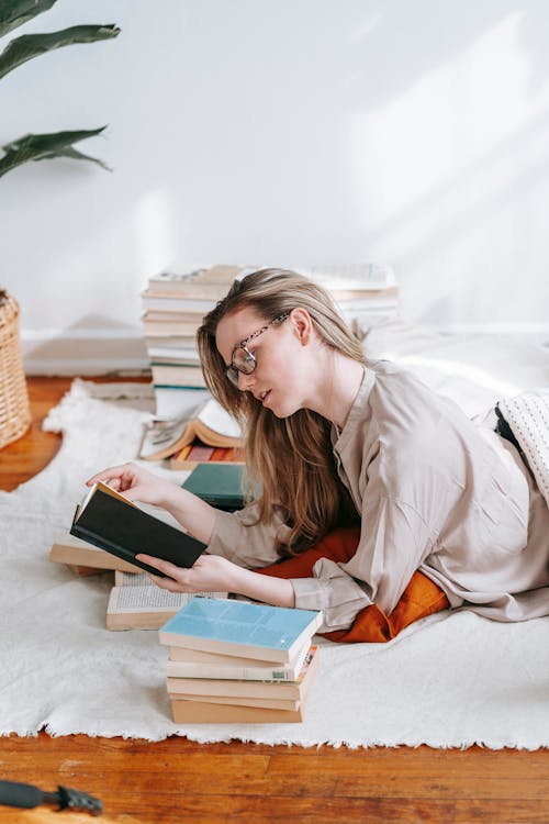 Focused student reading textbook while studying on carpet in house ...