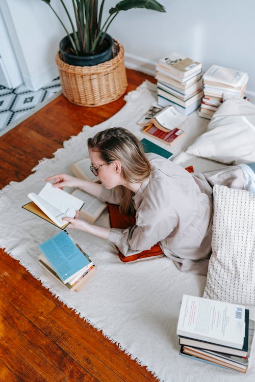 Free Young woman reading different books for research Stock Photo
