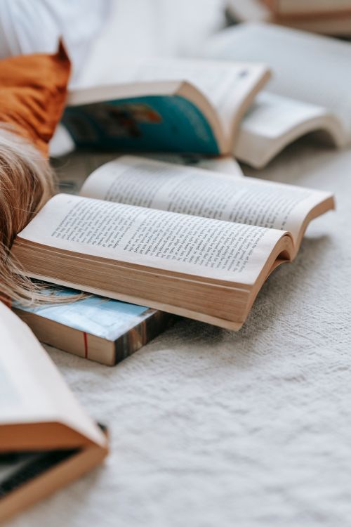 Free Abundance of opened books with text on pages placed on soft white fabric in light room at home on blurred background Stock Photo