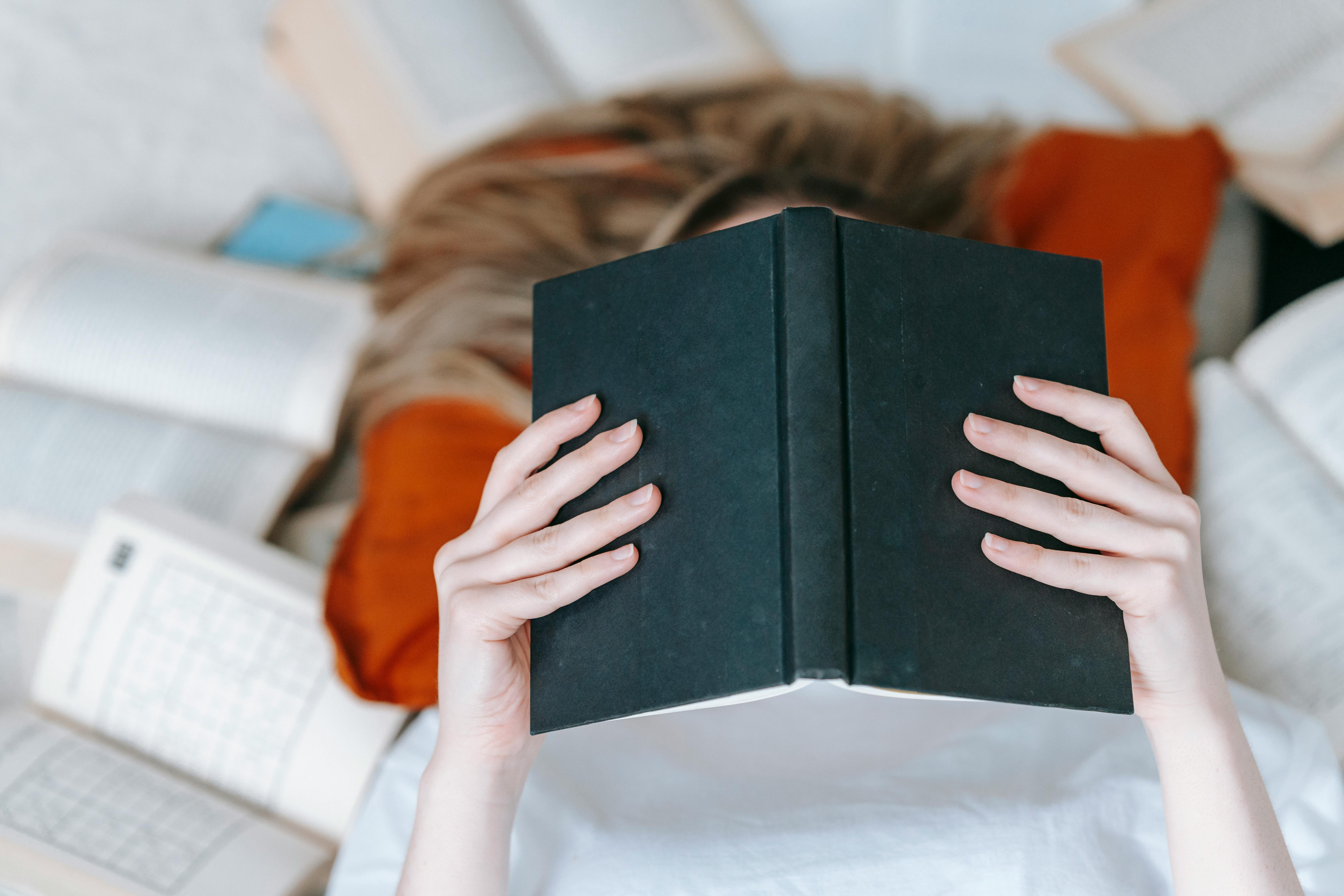 anonymous woman reading book near literature