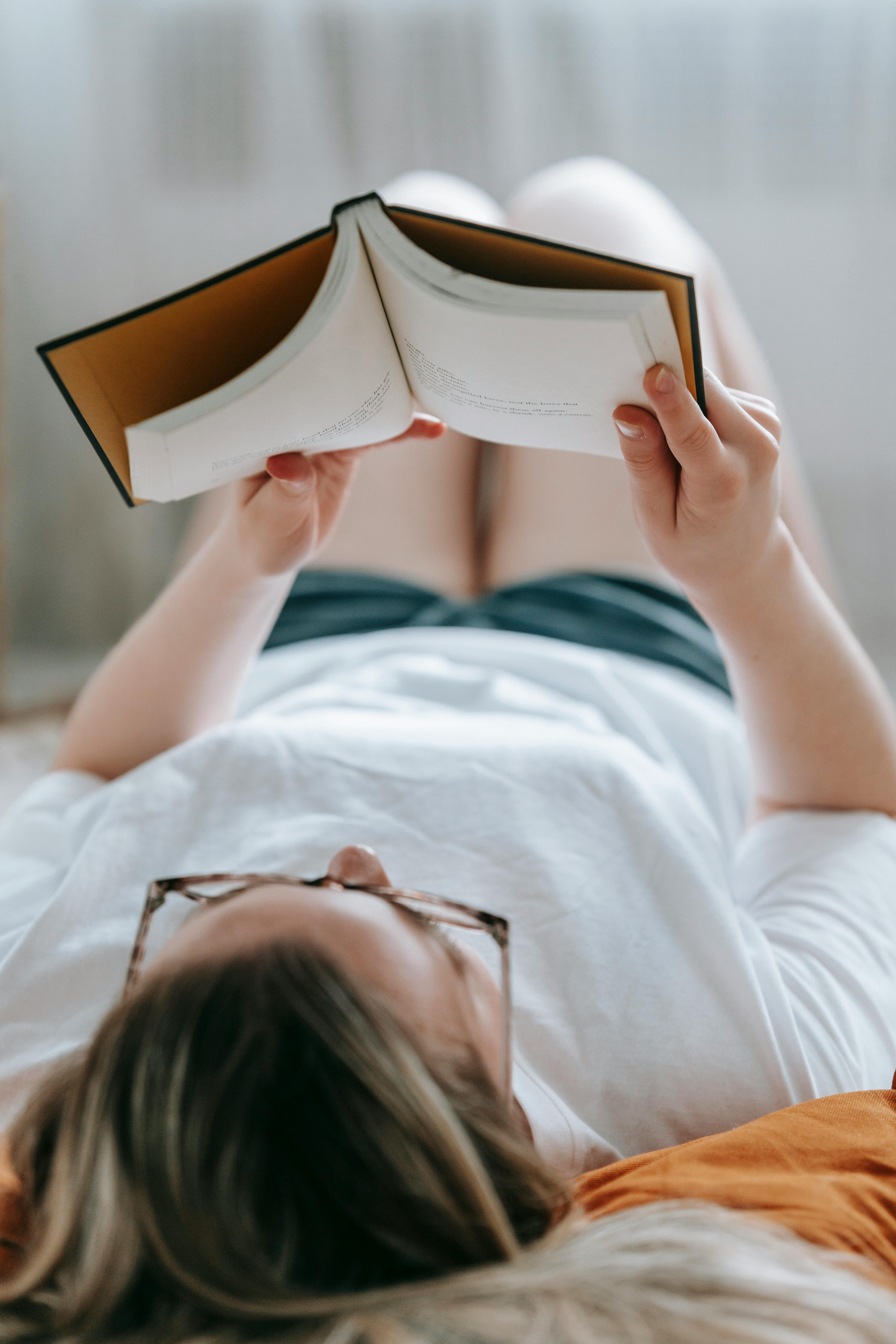 faceless woman reading book in room