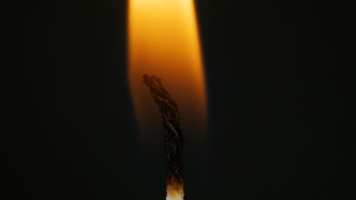 Free Intimate close-up of a candle wick burning with a soft flame against a dark background. Stock Photo