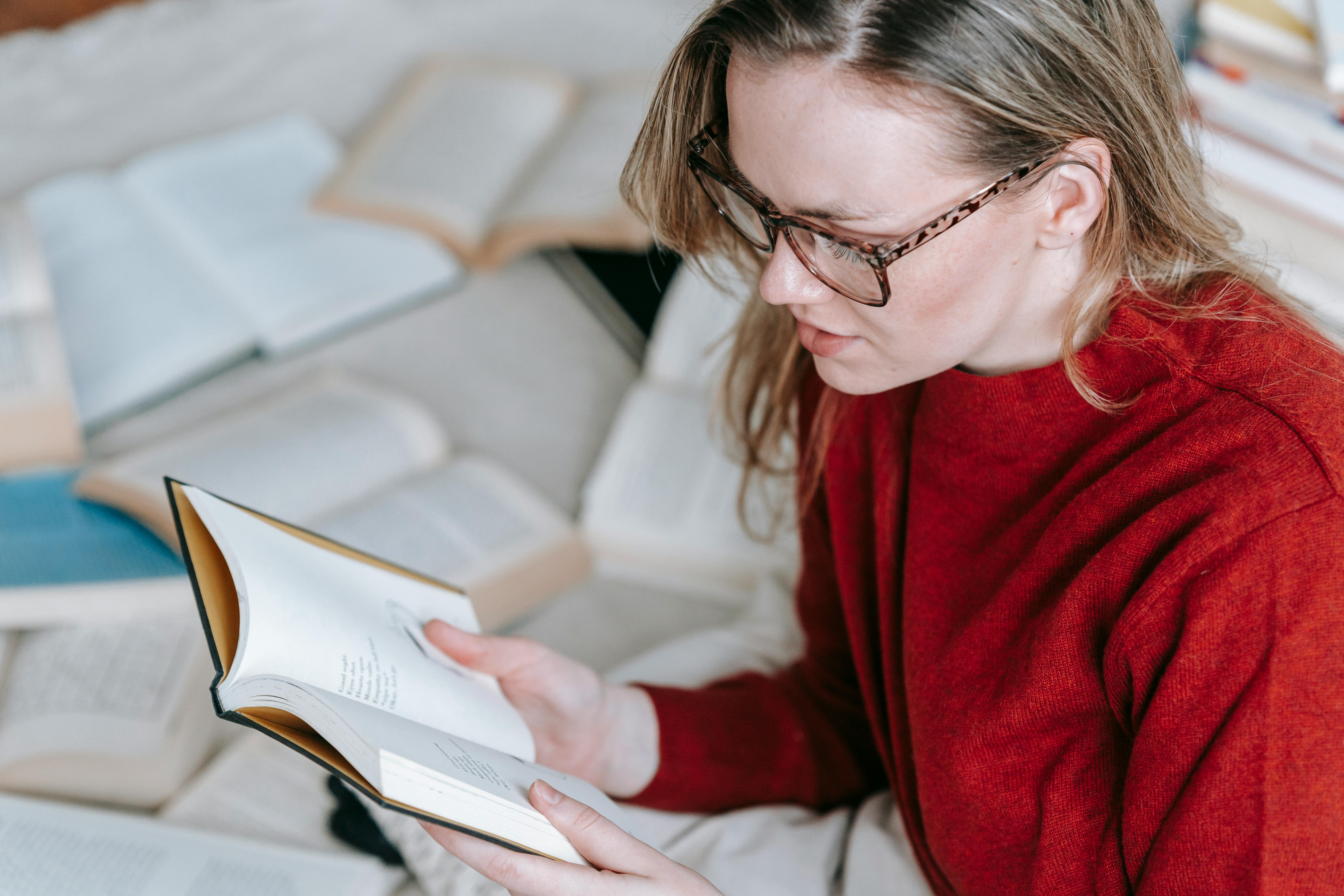 focused woman in eyeglasses reading book