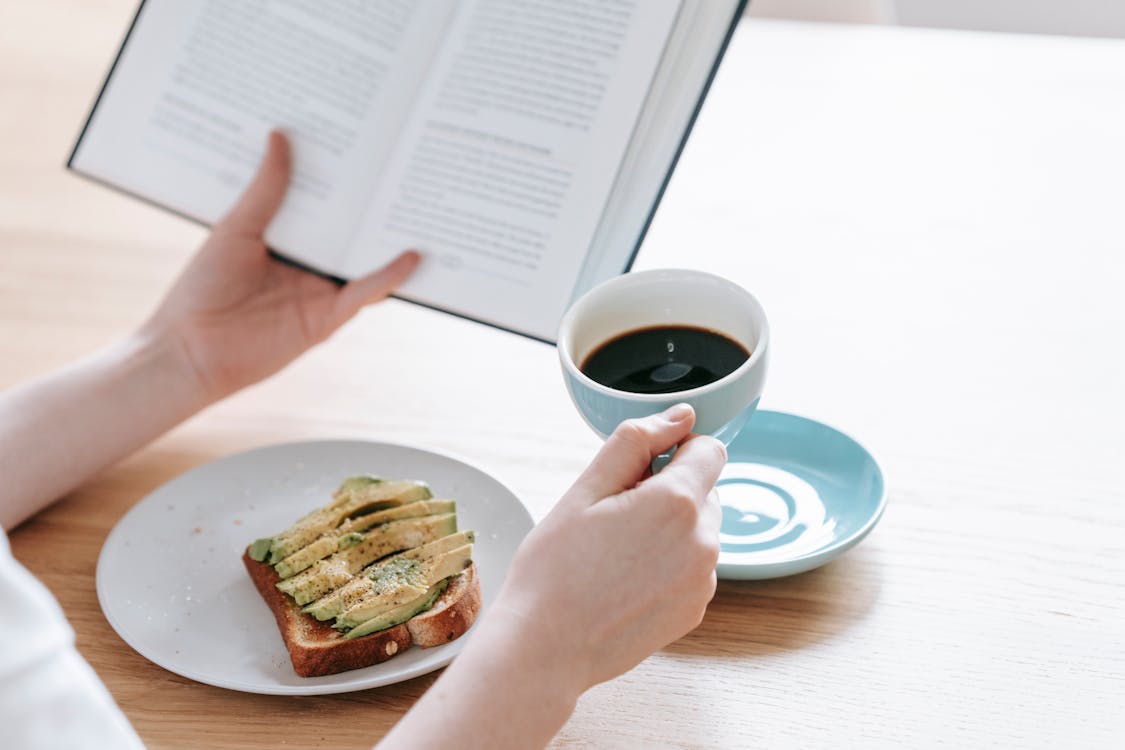 Free Crop person with cup of americano and book Stock Photo