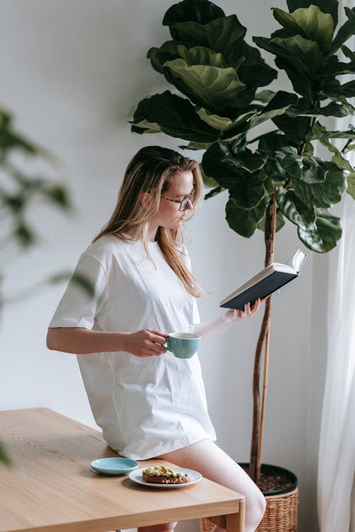 Free Woman immersed in book having breakfast Stock Photo