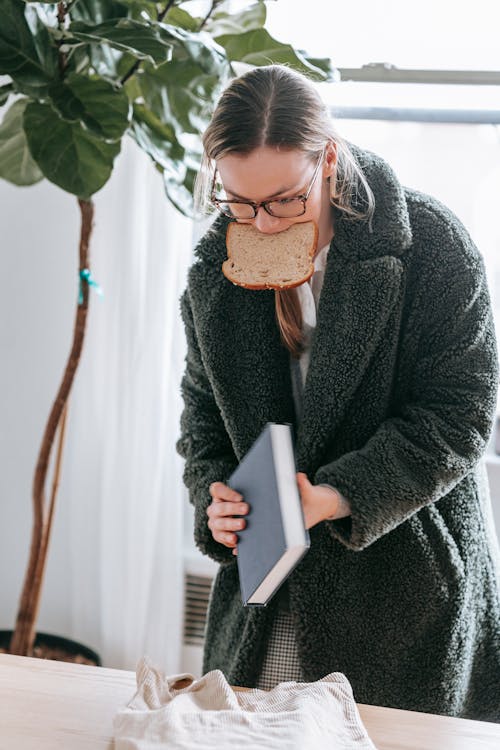 Free Woman with book and bread in warm clothes at home Stock Photo