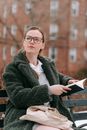 Pensive woman sitting on bench and reading book