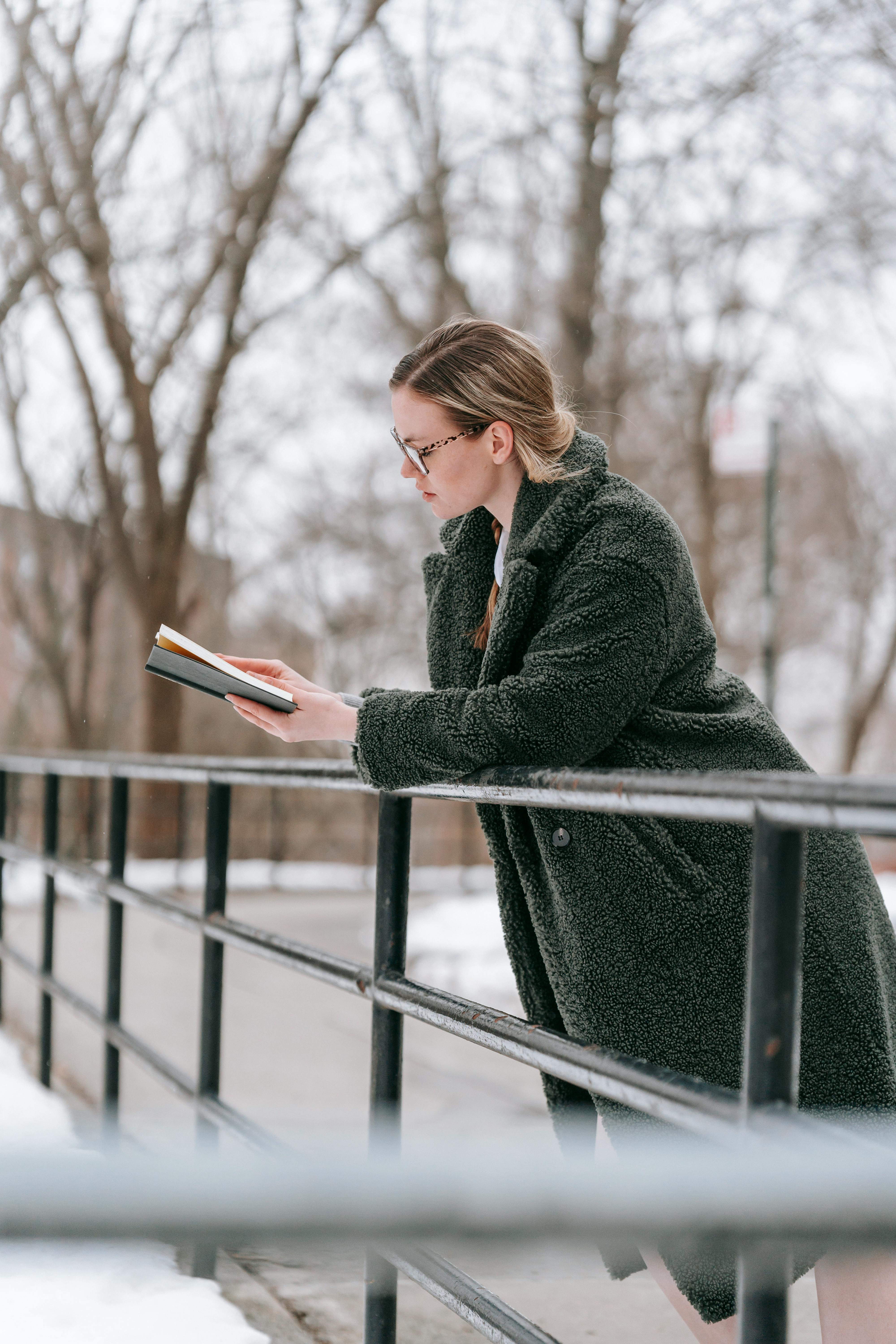 pensive woman reading book in cold park