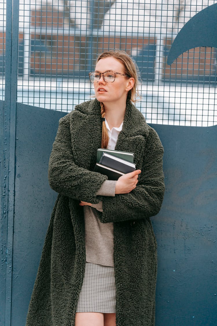 Young Woman With Books Standing Near Gates