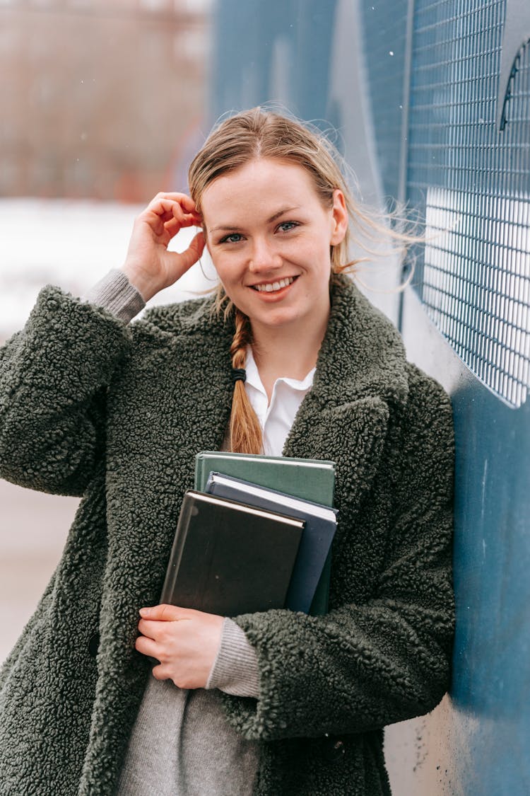 Content Student With Books Touching Flying Hair On Street