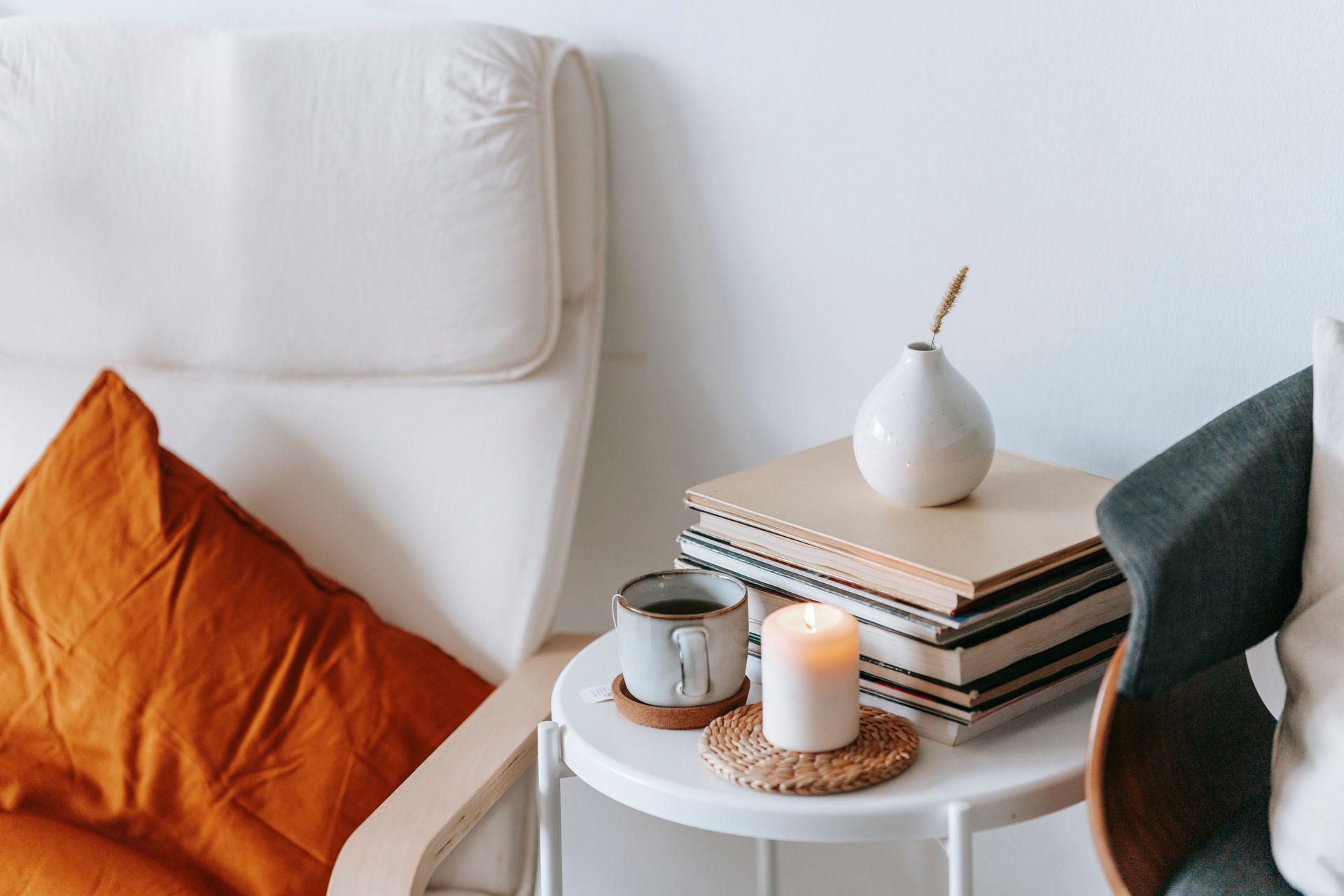 Table with tea and burning candle between armchairs in house